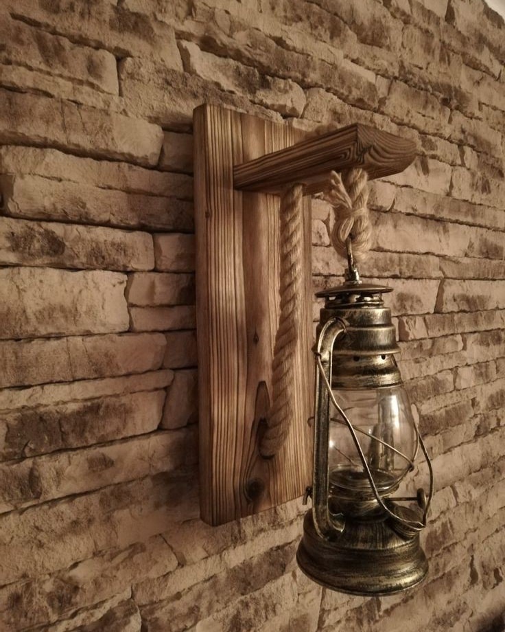 A vintage oil lantern hanging on a rustic wooden sconce against a brick wall