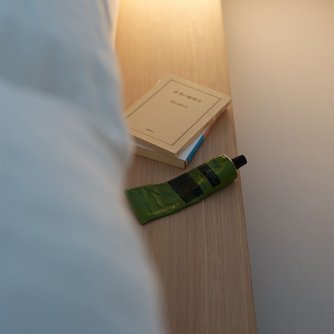 A neatly arranged bedside with a book and a tube of hand cream