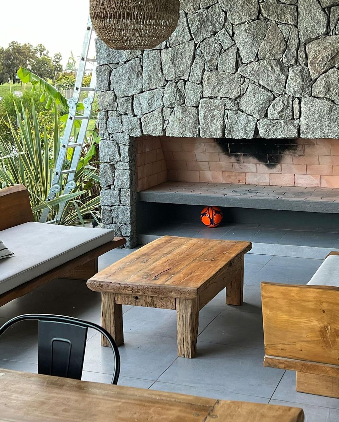 A cozy outdoor living area with rustic wooden furniture and a stone fireplace