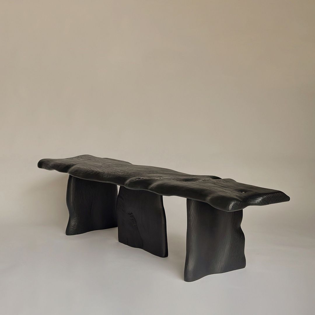 A sculptural modern bench crafted from a single piece of charred wood