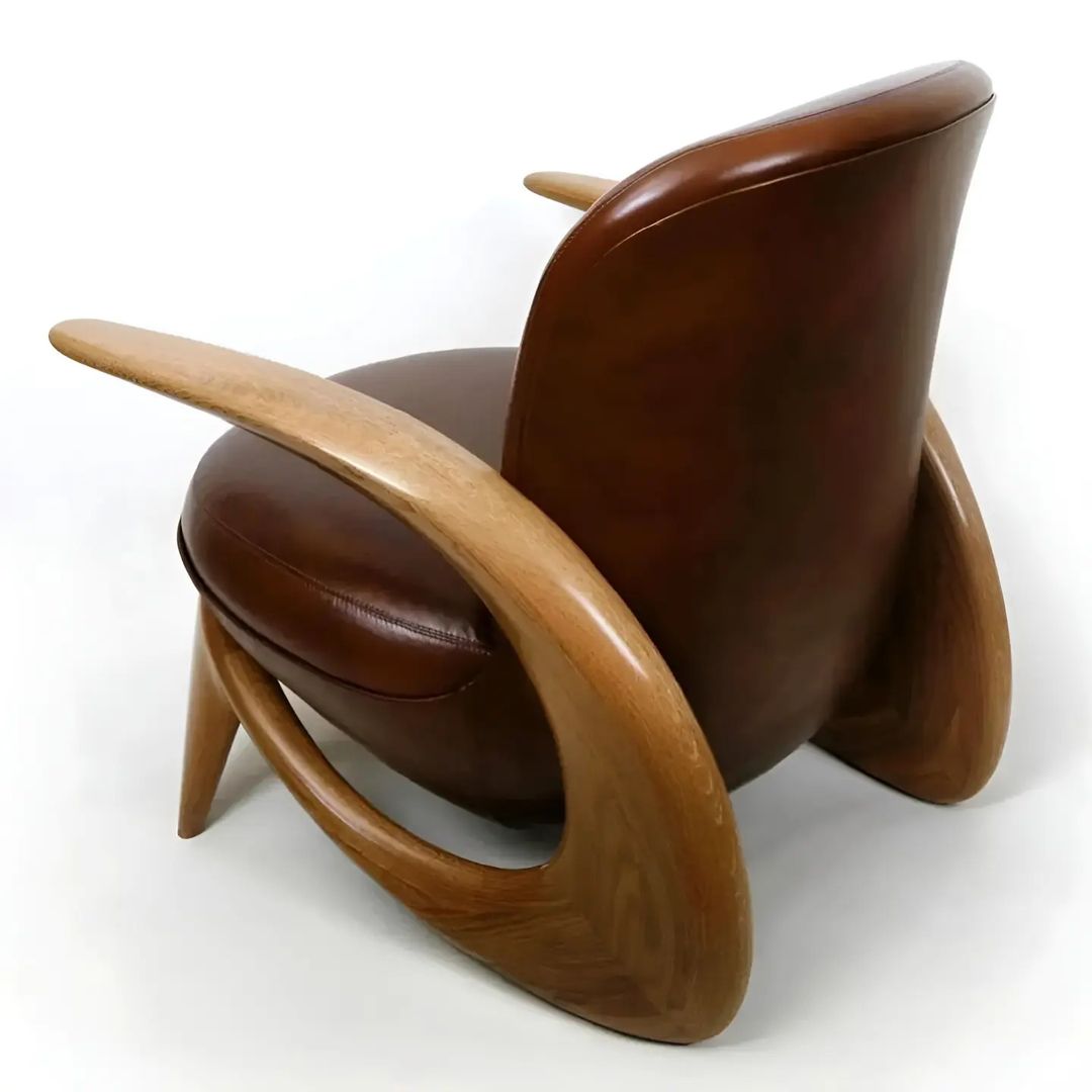 A uniquely designed armchair with a wood frame and brown leather upholstery