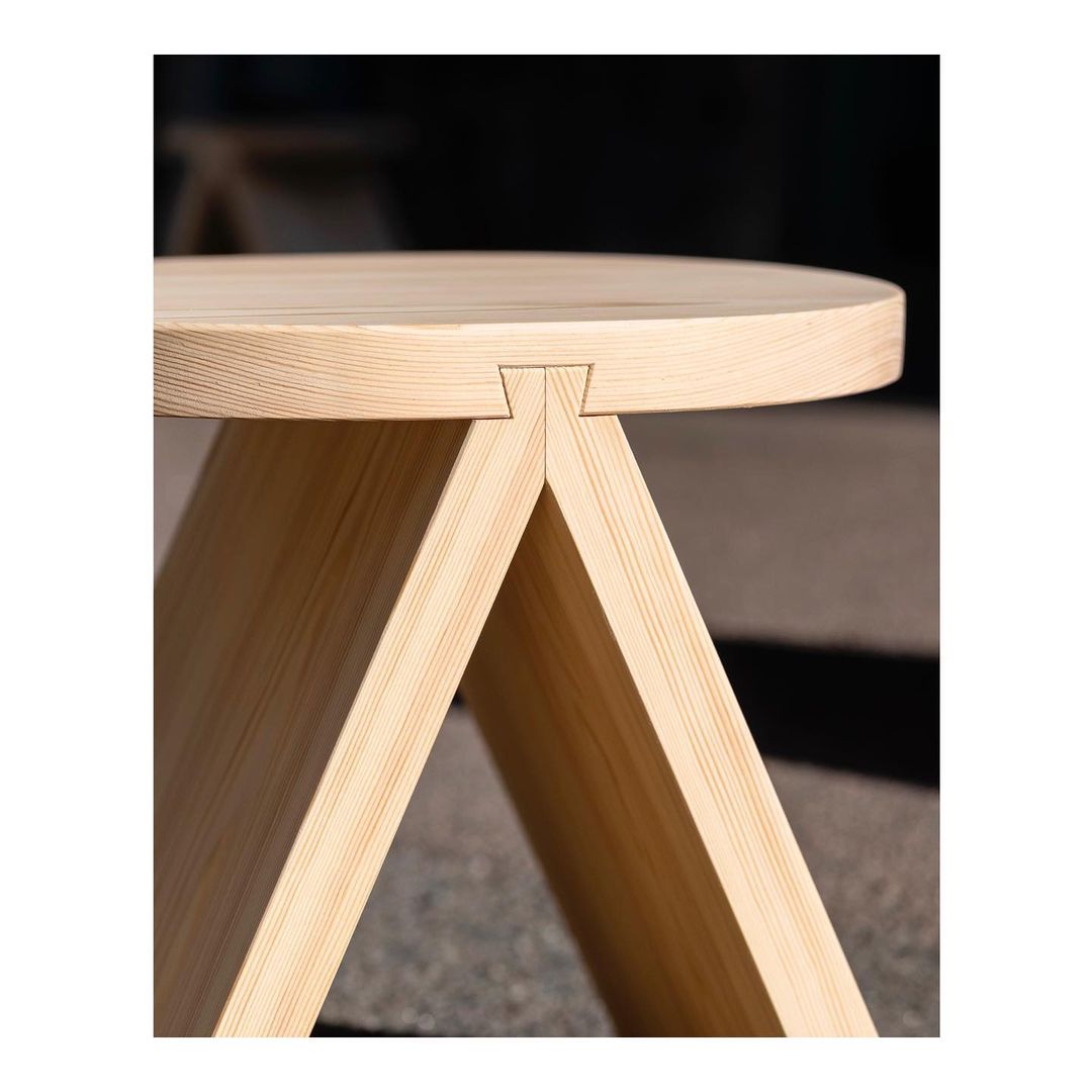 Clean and minimalist three-legged wooden table displaying joinery detail