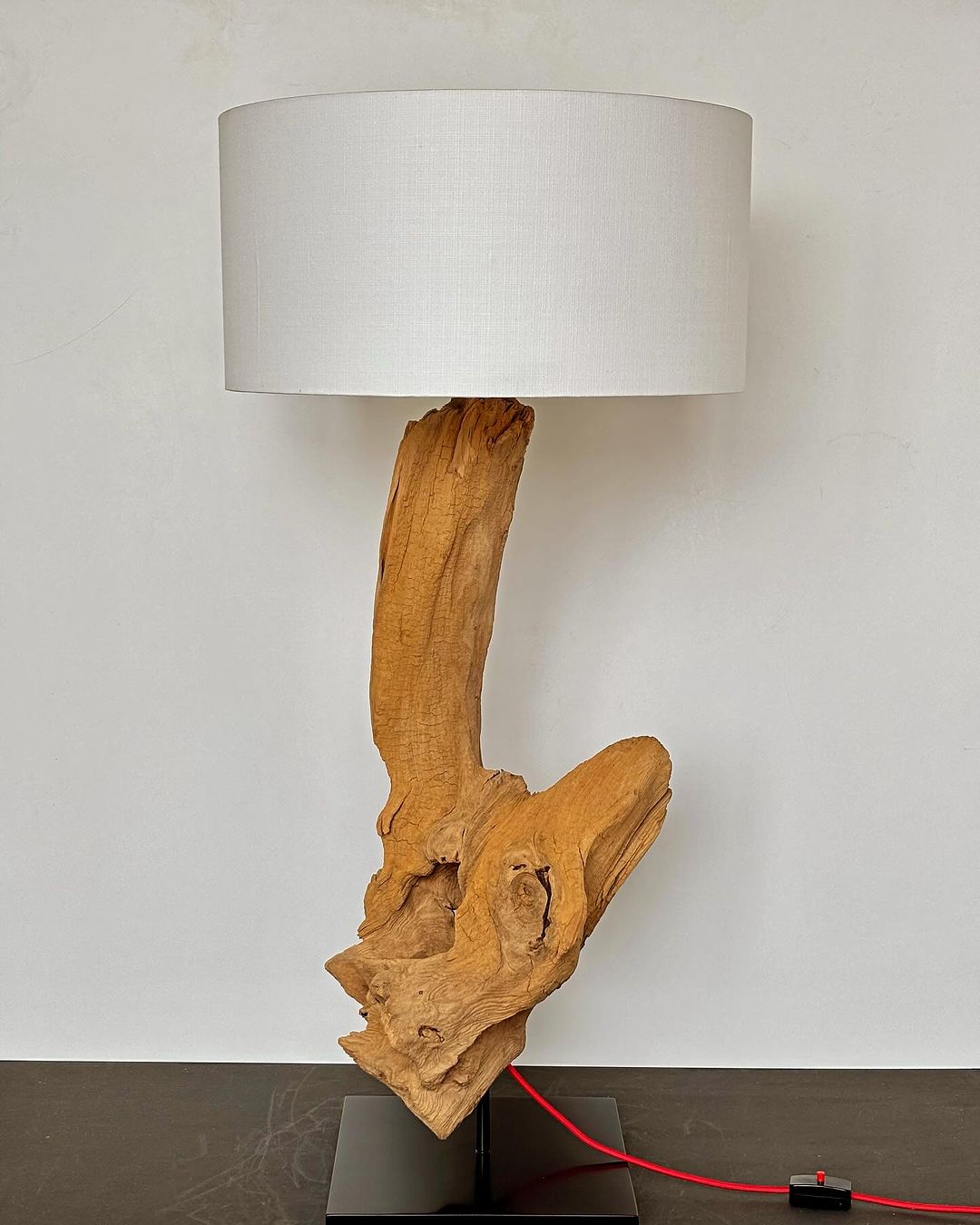 A sculptural table lamp with a raw wood base