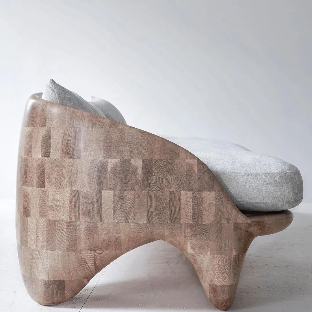 A unique wooden chaise lounge with a plush light grey cushion