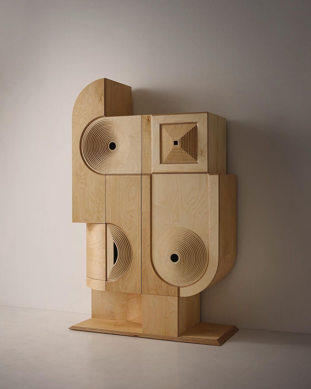 Abstract wooden sculpture resembling a set of drawers with circular patterns