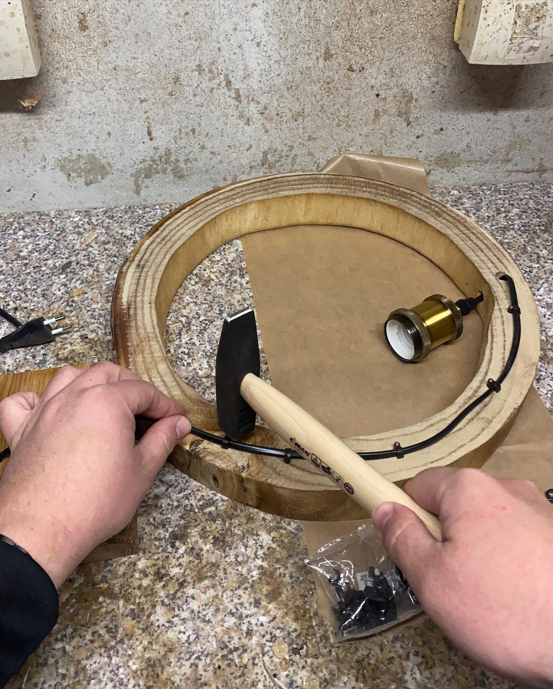 A person assembling the components of a wooden lamp