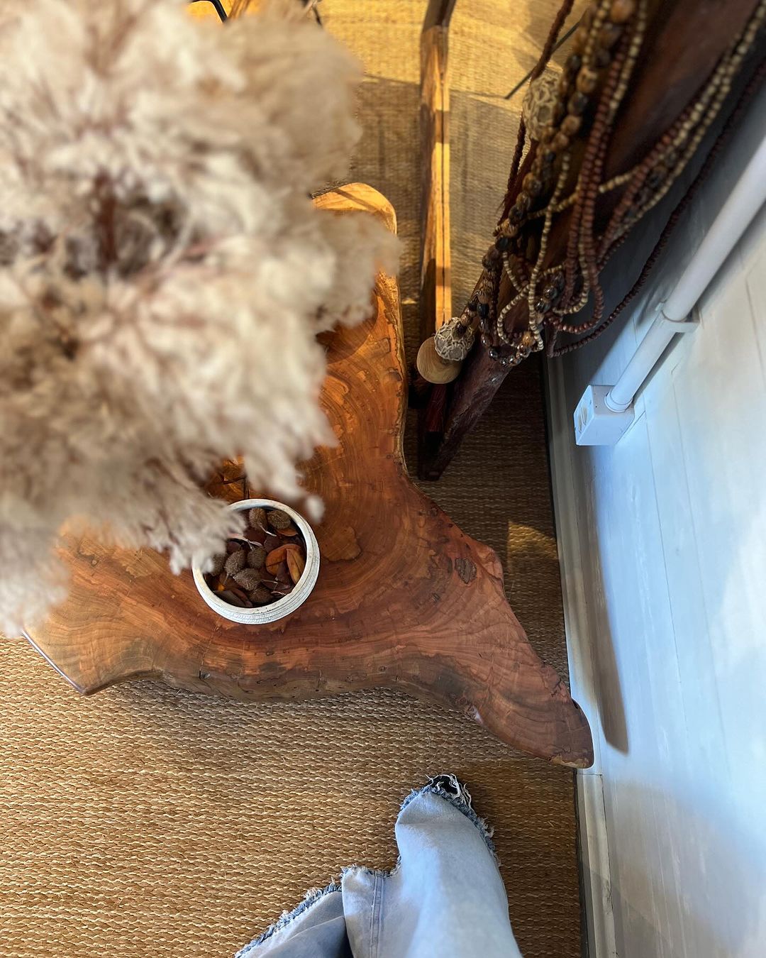 An intricately carved wood side table holding a dog's food bowl