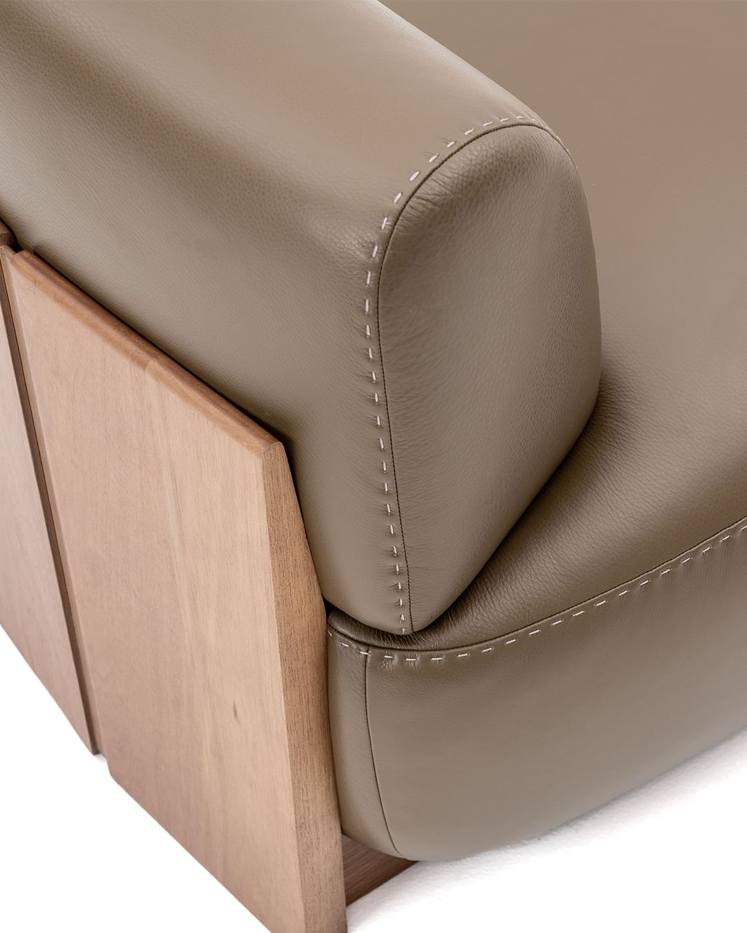 A tasteful blend of materials featuring a plush leather cushion with precision stitching, nestled against a smooth wooden frame.