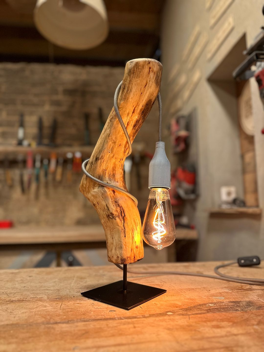 An artfully crafted wood lamp with a single exposed filament bulb