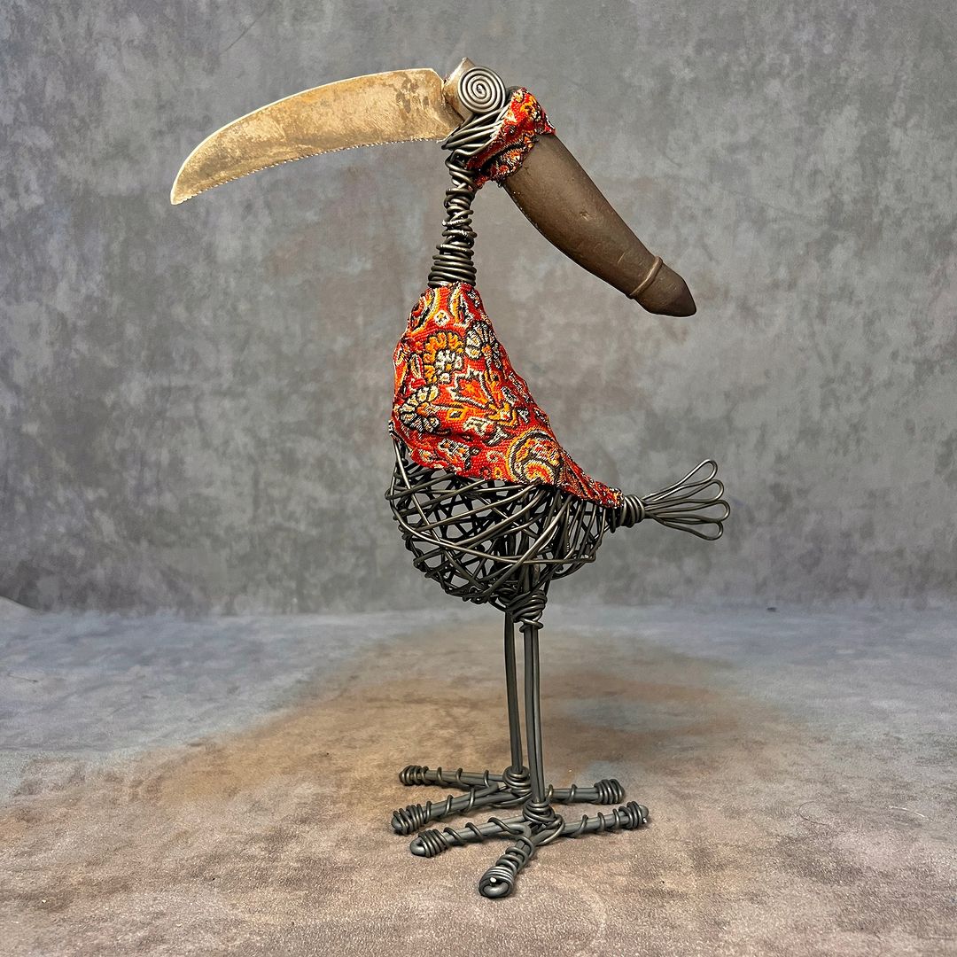 A whimsical sculpture of a bird with a colorful paisley body and metal wire framework