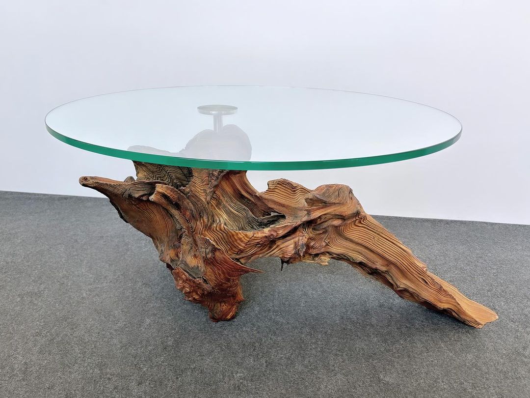 A unique coffee table with a glass top and a natural wooden base