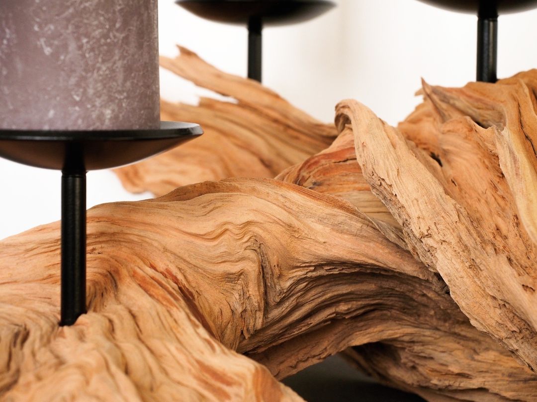 An intricate piece of driftwood supporting a modern candle holder