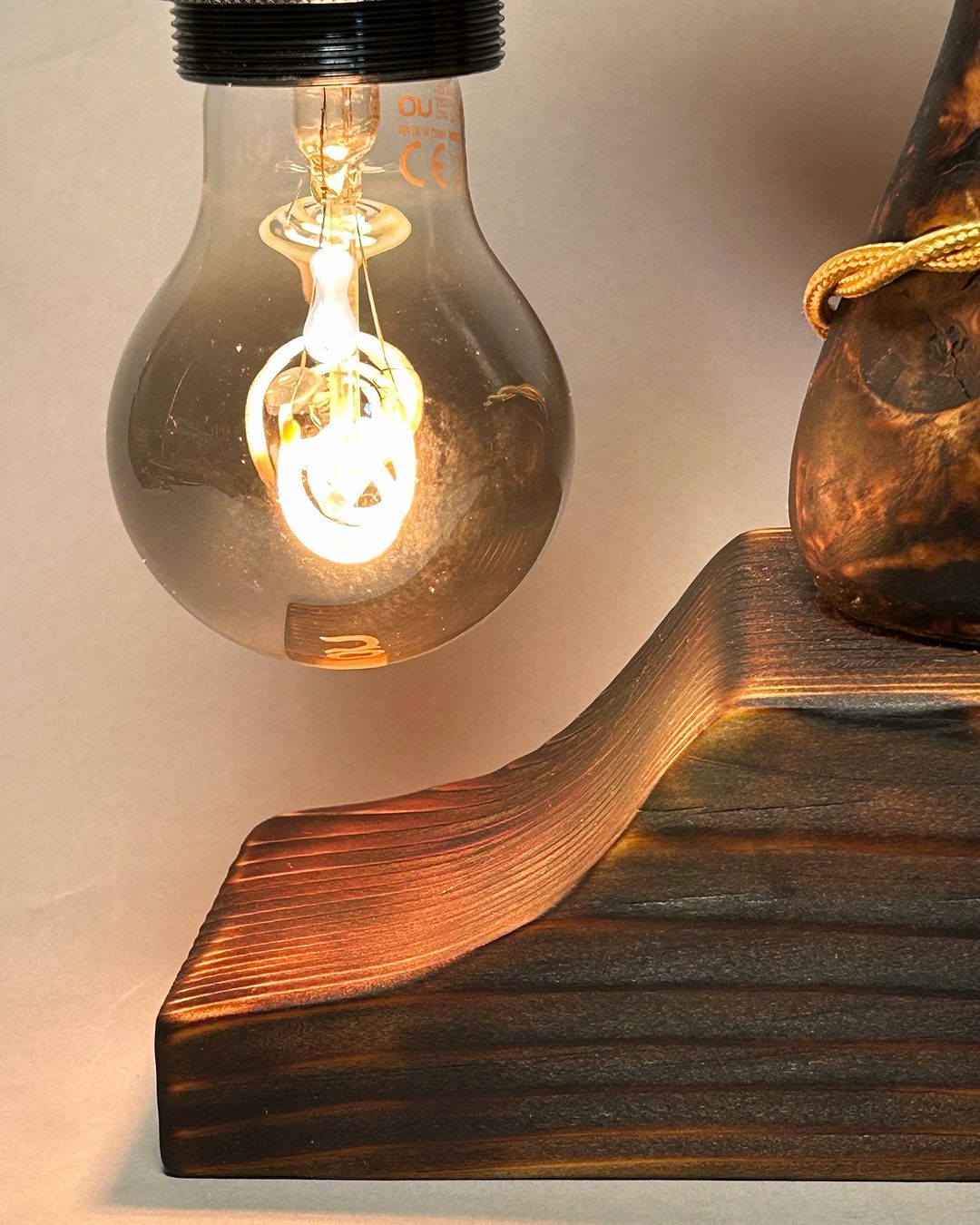 A wooden sculpture accentuated by the warm glow of an adjacent illuminated light bulb