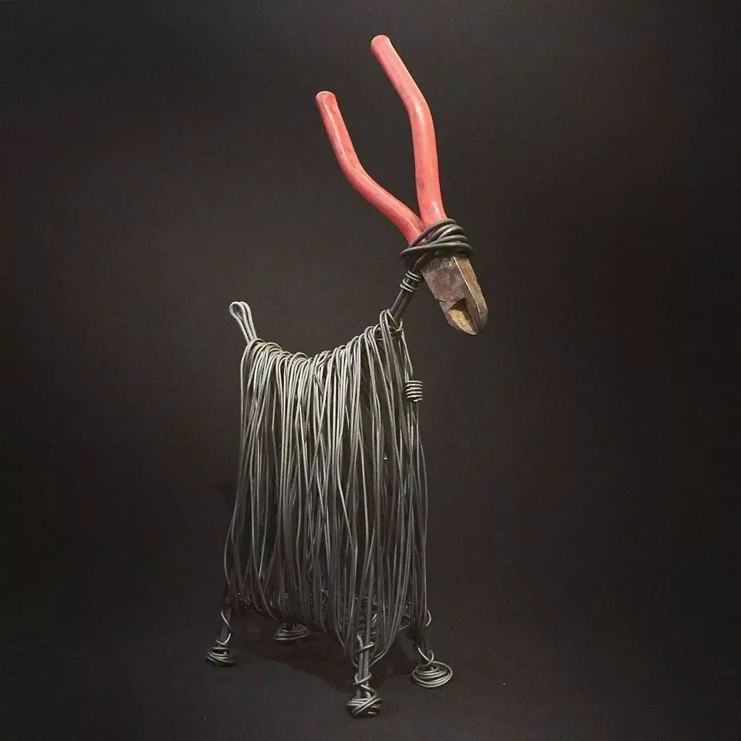 Artistic metal sculpture resembling a goat with red tools as horns