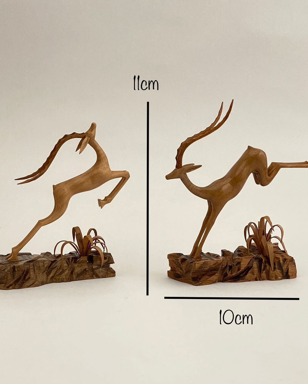 An exquisite pair of wooden sculptures depicting graceful gazelles in motion