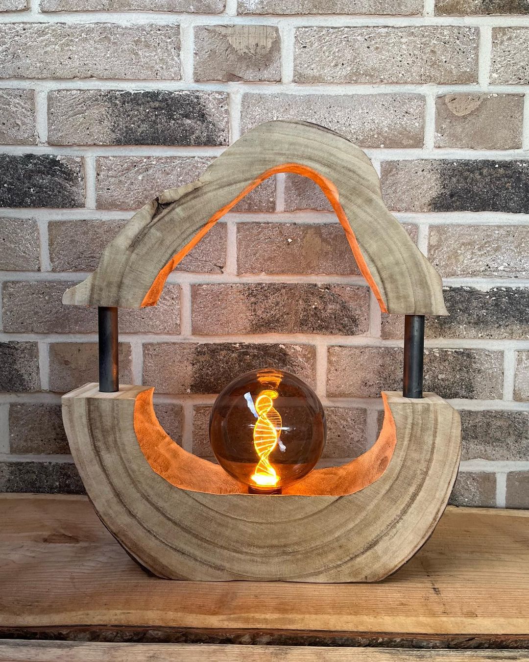 A unique wooden lamp with curved layers and a glowing Edison bulb