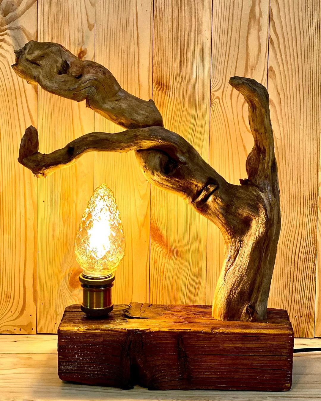 A uniquely crafted wooden lamp with a glowing bulb