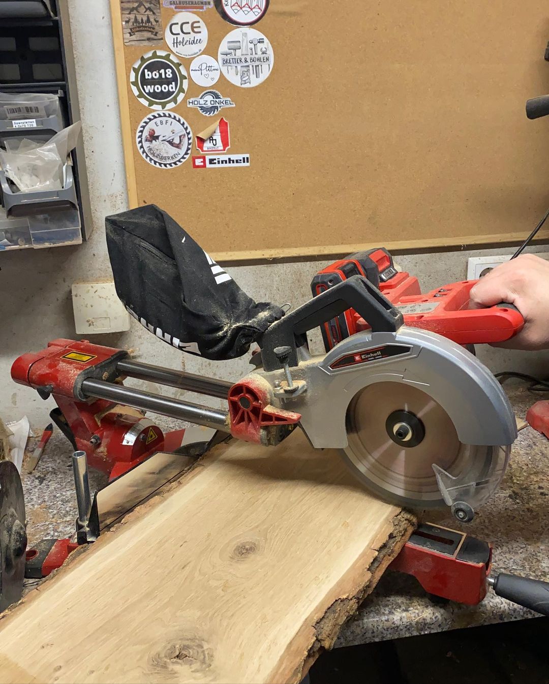 A person operating a compound miter saw on a plank of wood