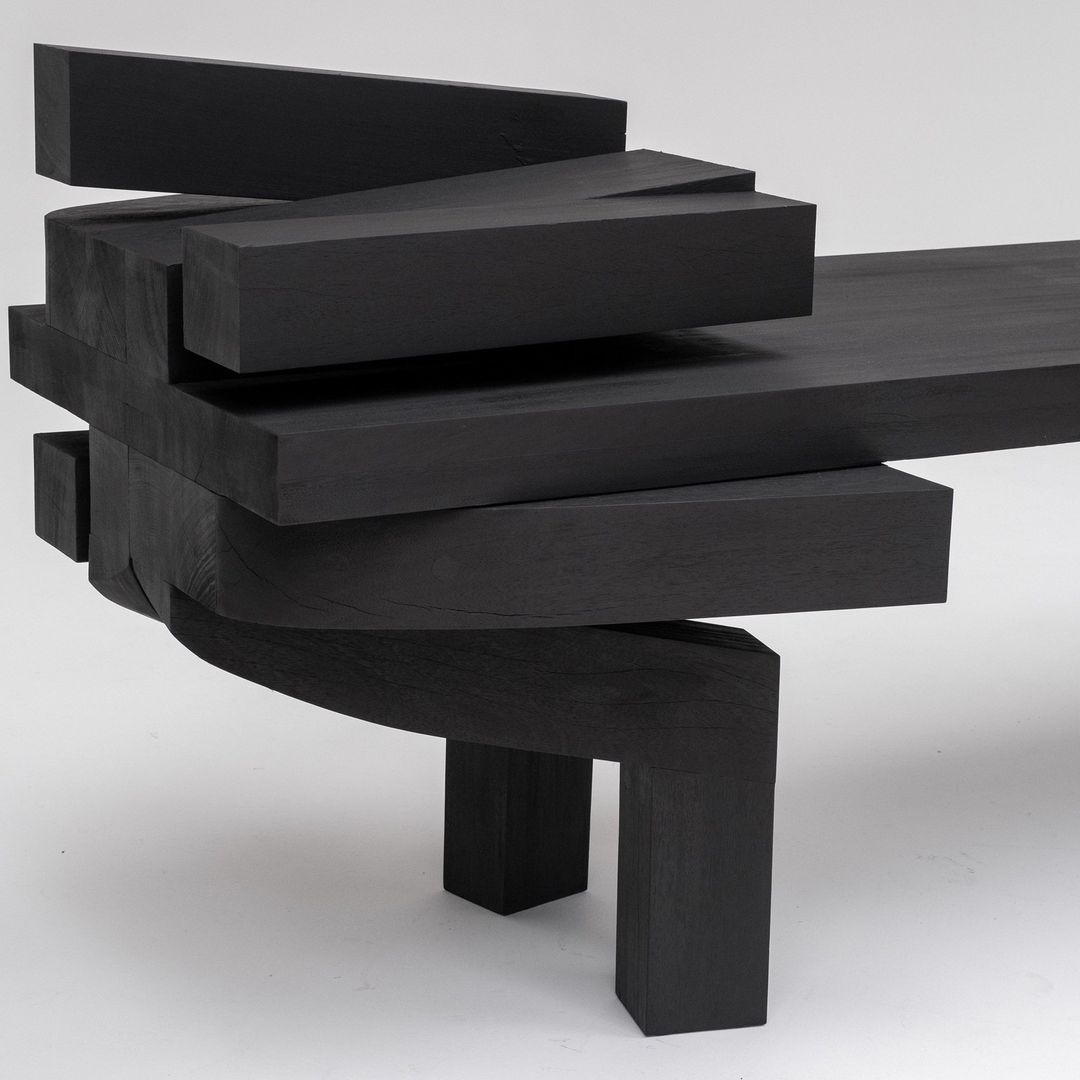 A uniquely designed black table with a staggered, geometric formation of planks creating a dynamic sense of motion.