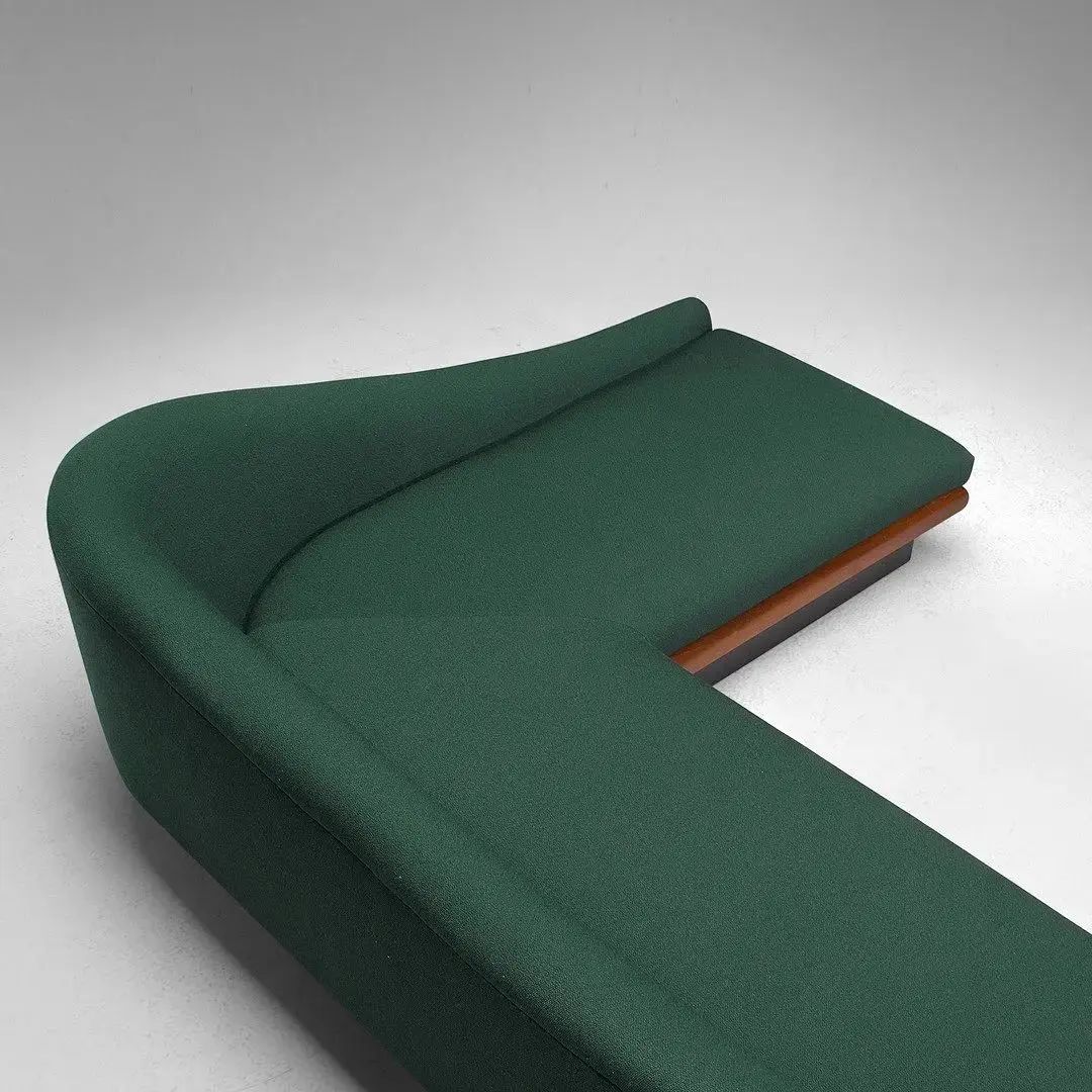 A modern dark green sofa featuring a sleek contour and wooden accents