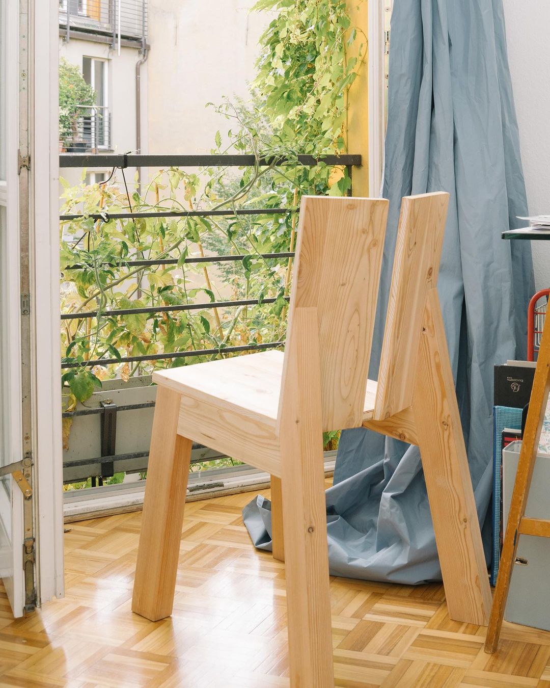 A minimalist wooden chair placed near a balcony door, showcasing a trendy fusion of functionality and simplicity.