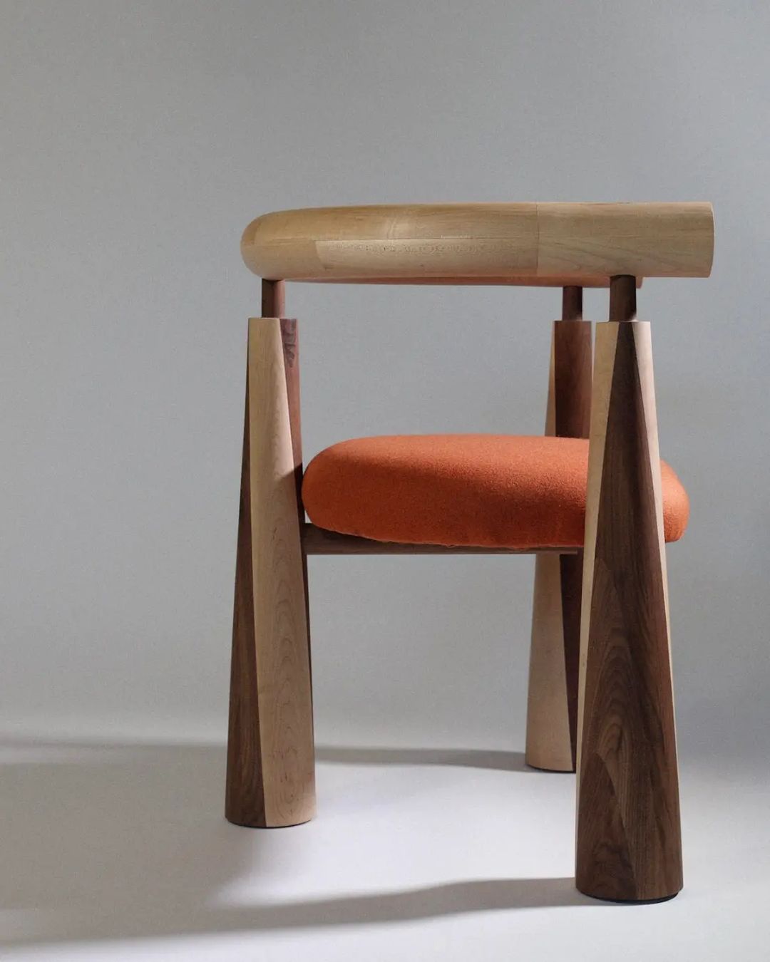 A uniquely designed chair with a cylindrical backrest and contrasting wooden legs