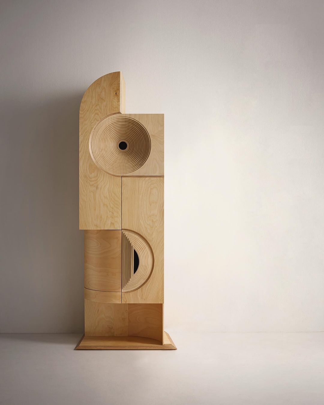 A modern wooden sculpture with geometric shapes and circular cutouts