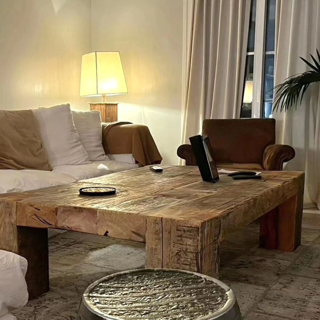 A simplistic and rustic living room with a large wooden coffee table