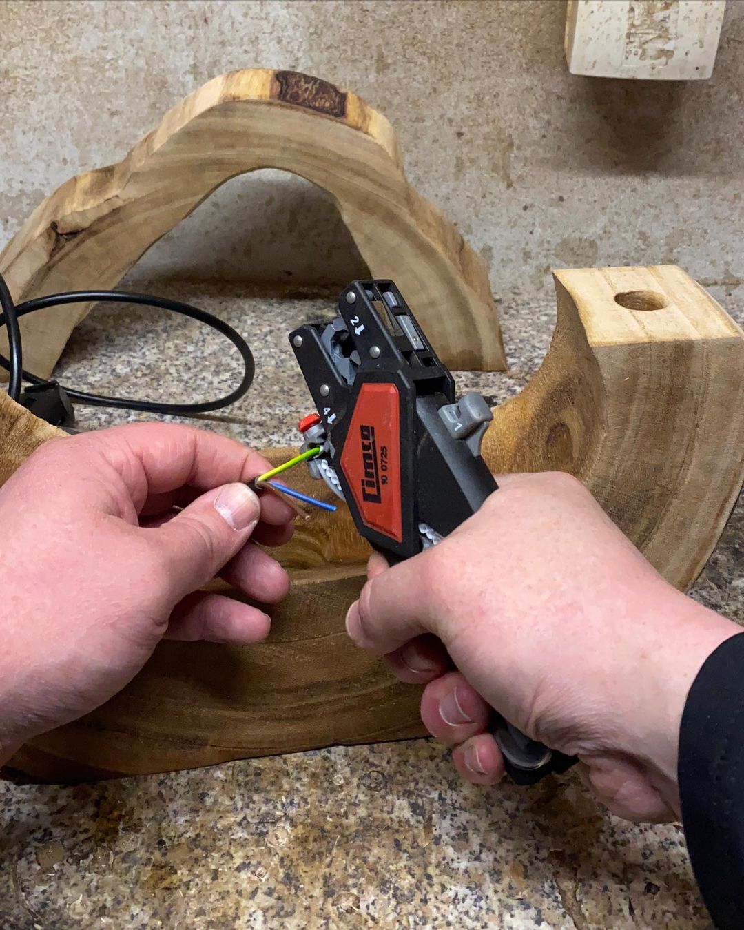 A person splicing electrical wires with a crimping tool