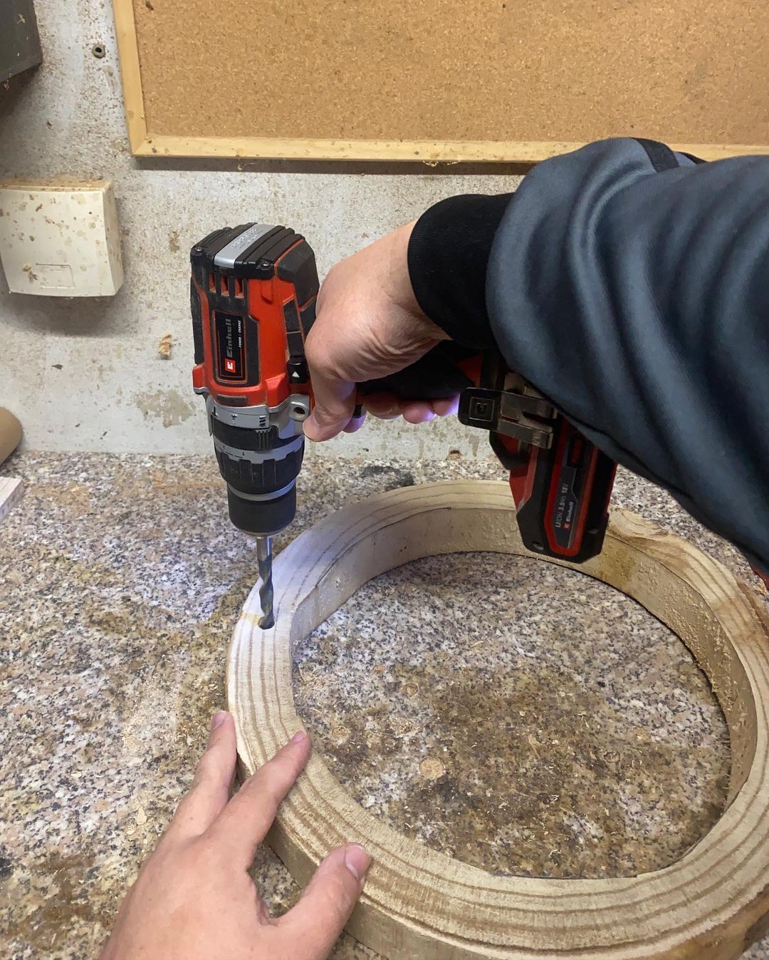 Person using a cordless drill to make a hole in a wood layer