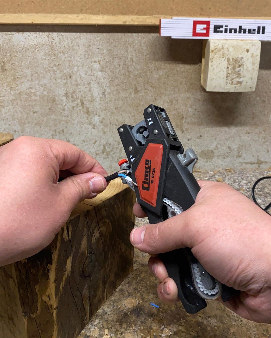 Person using a wire crimping tool on a cable