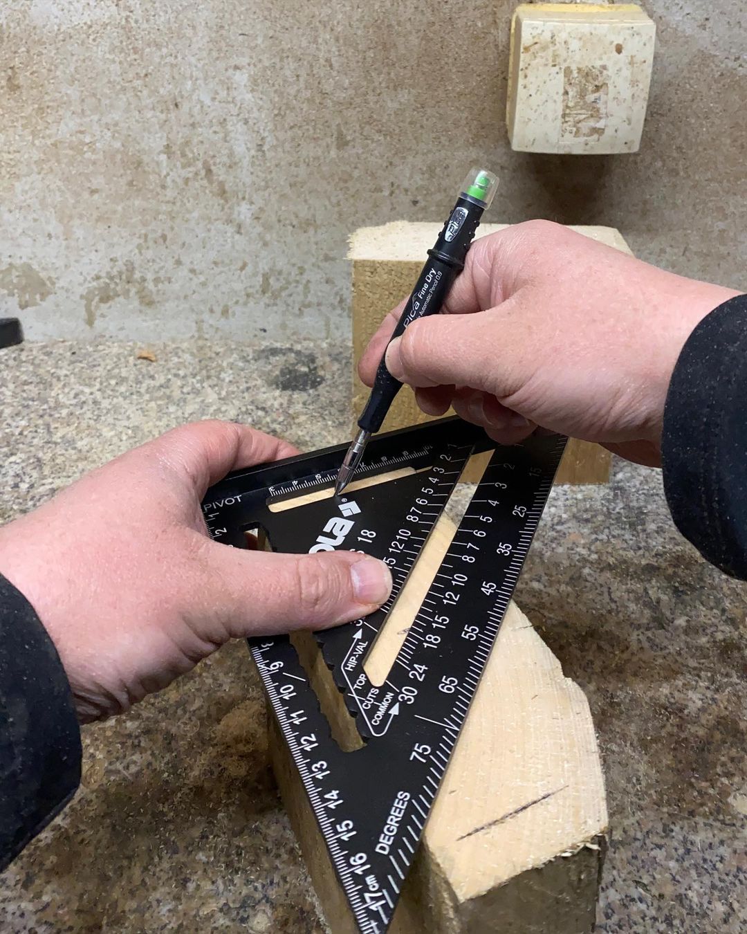 Person measuring a piece of wood with a speed square and marking with a pencil