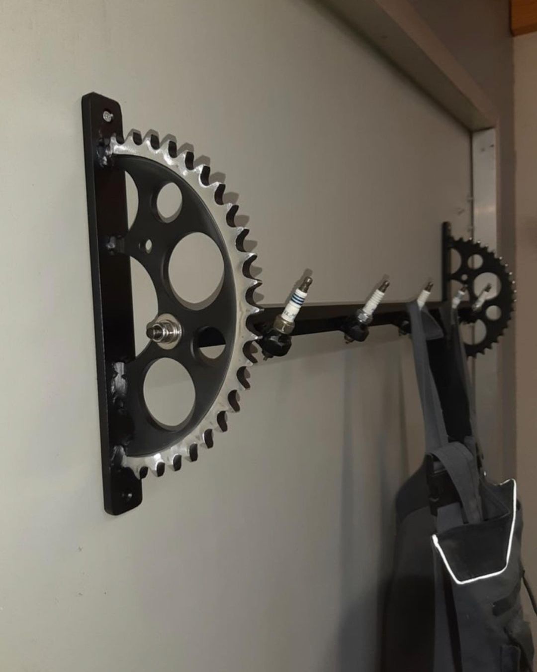 A wall-mounted gear and spark plug coat rack in a minimalist style