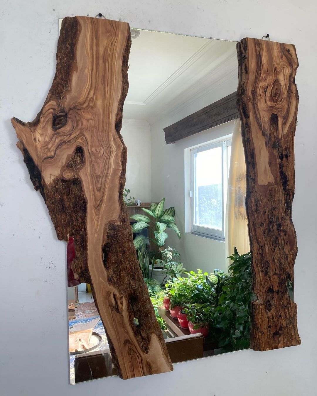 A uniquely designed mirror framed with natural edge wood slabs on both sides