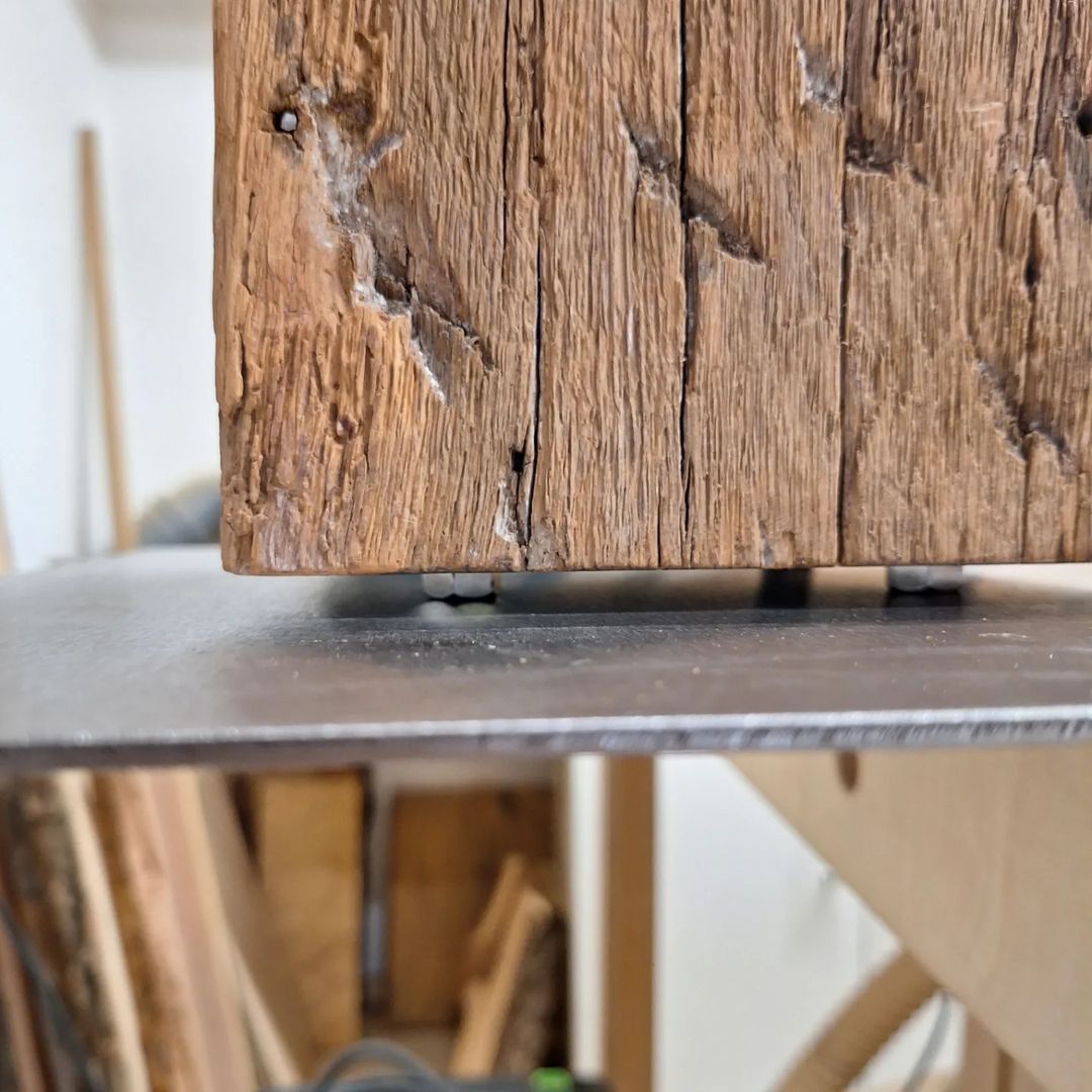 A rustic wooden beam revealing its textured grain as it rests upon a sleek metal surface.