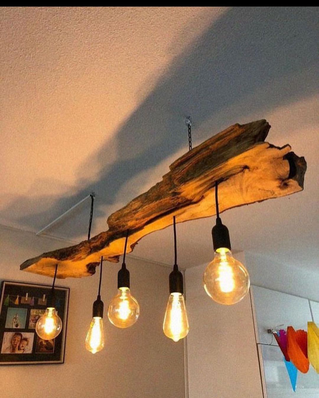 A unique DIY pendant light fixture made from a reclaimed piece of wood, with Edison bulbs hanging at varying lengths