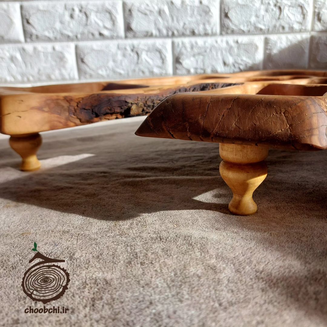 A unique wooden serving tray with intricate natural patterns and raised on rounded legs.