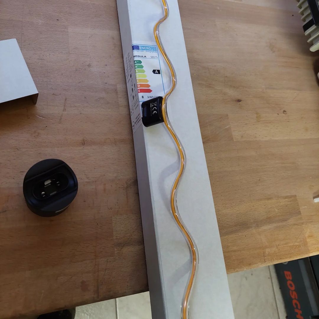 A creatively routed electrical cable on a wooden workbench that resembles a wave