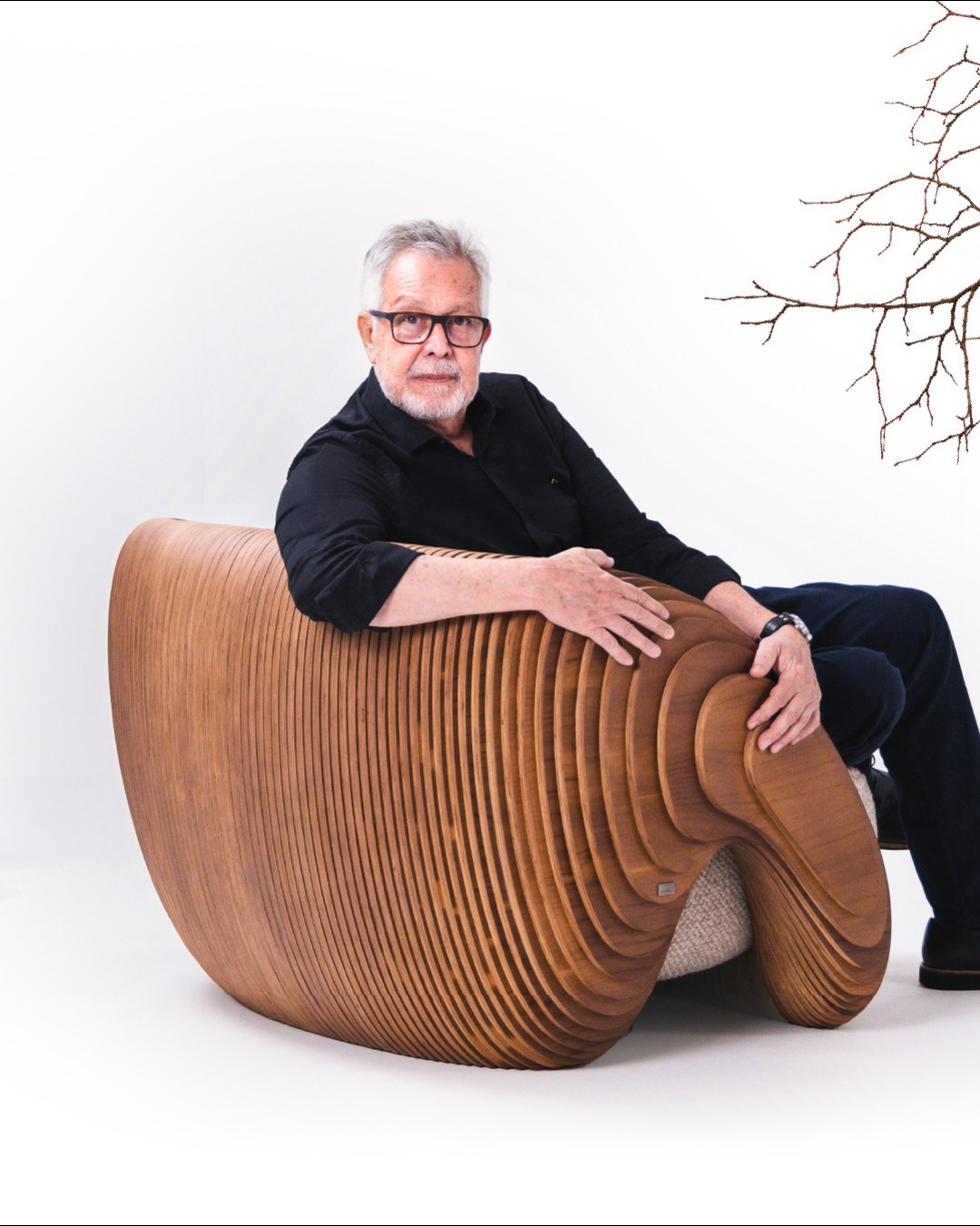 A visionary individual posing confidently on an innovative sculptural wooden chair