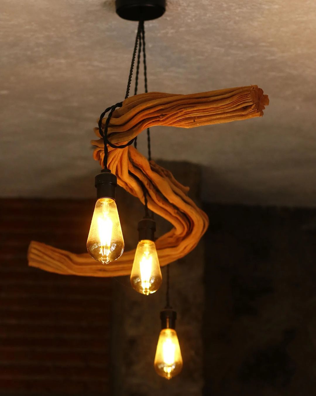 A creatively designed pendant light with exposed Edison bulbs entwined in a draped, yellow fabric.