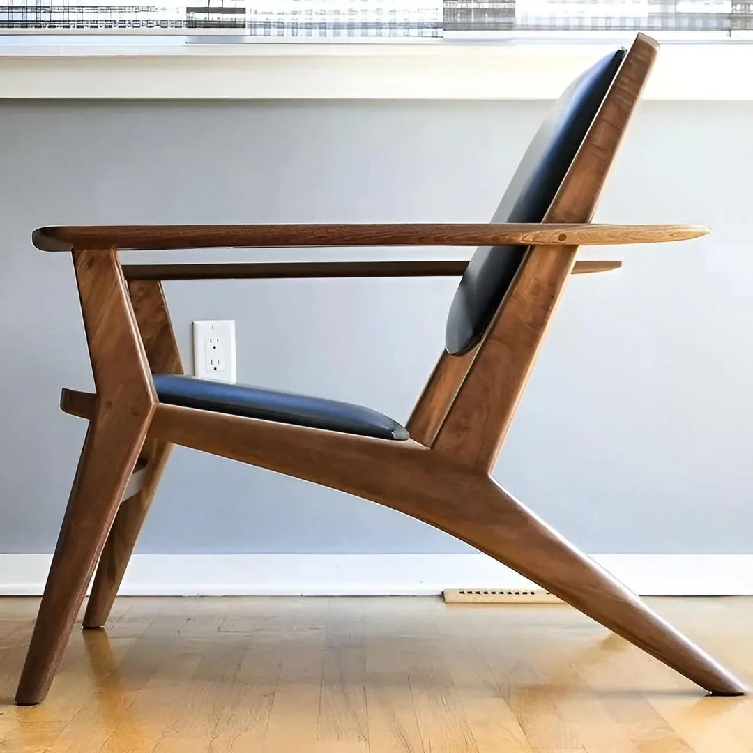 A unique wooden chair with a bold, angular design and blue leather upholstery