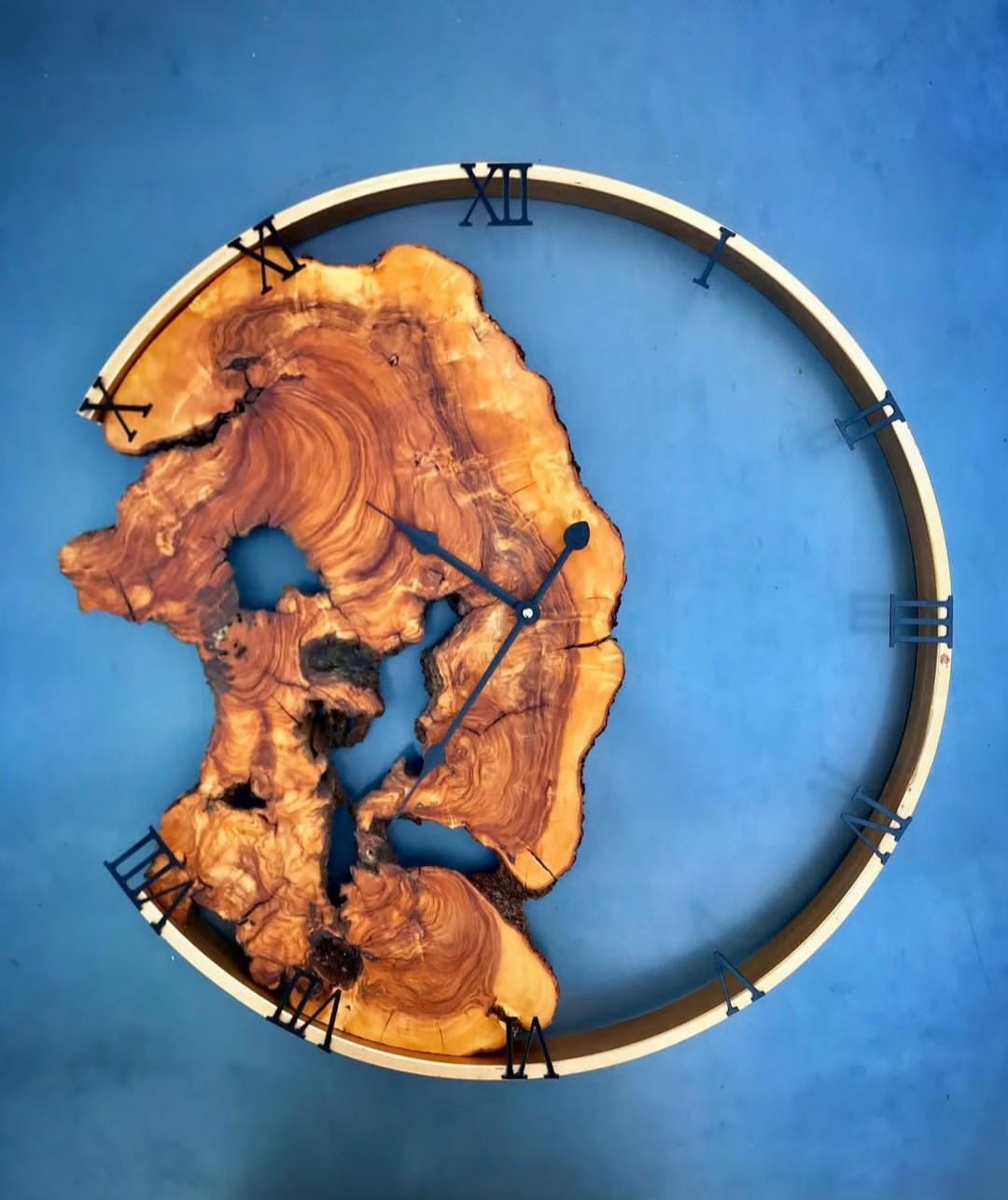 A unique wooden clock with Roman numerals on a metal ring surrounding an irregularly shaped polished wood slice