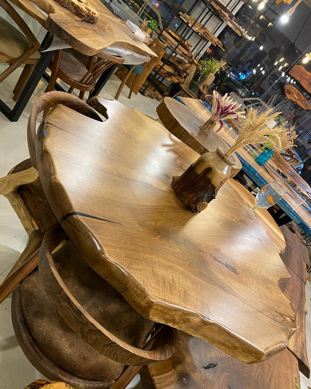 A uniquely shaped wooden table with cozy chairs in a modern cafe setting.