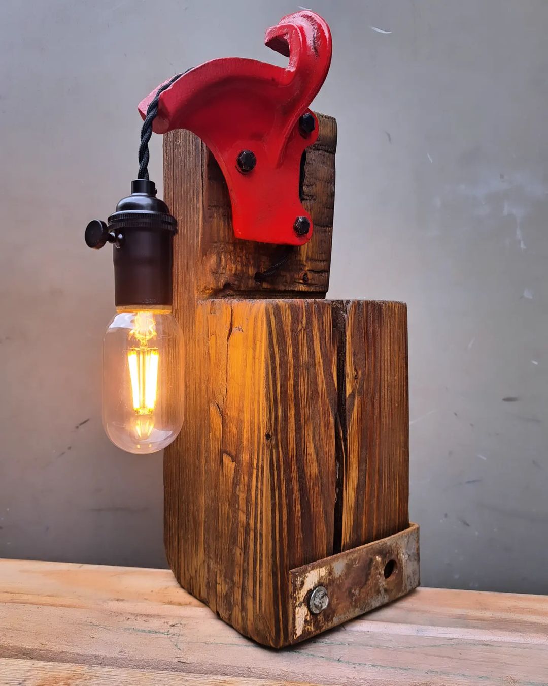 A creatively designed lamp combining rustic wood and a vibrant red pulley