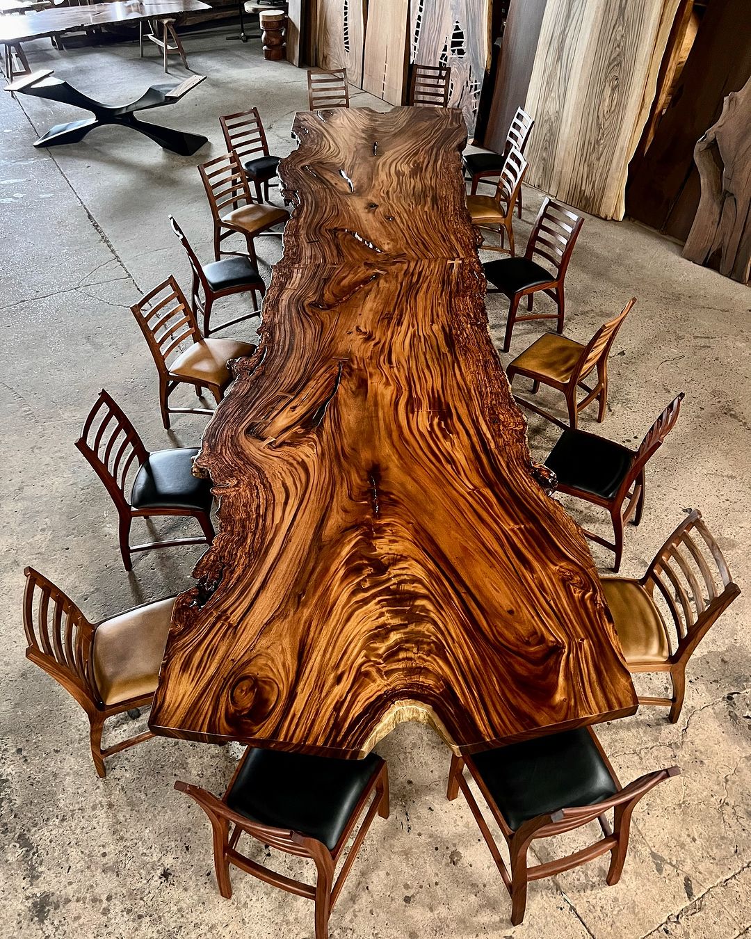 A magnificent live edge wood table flanked by a diverse set of classic chairs