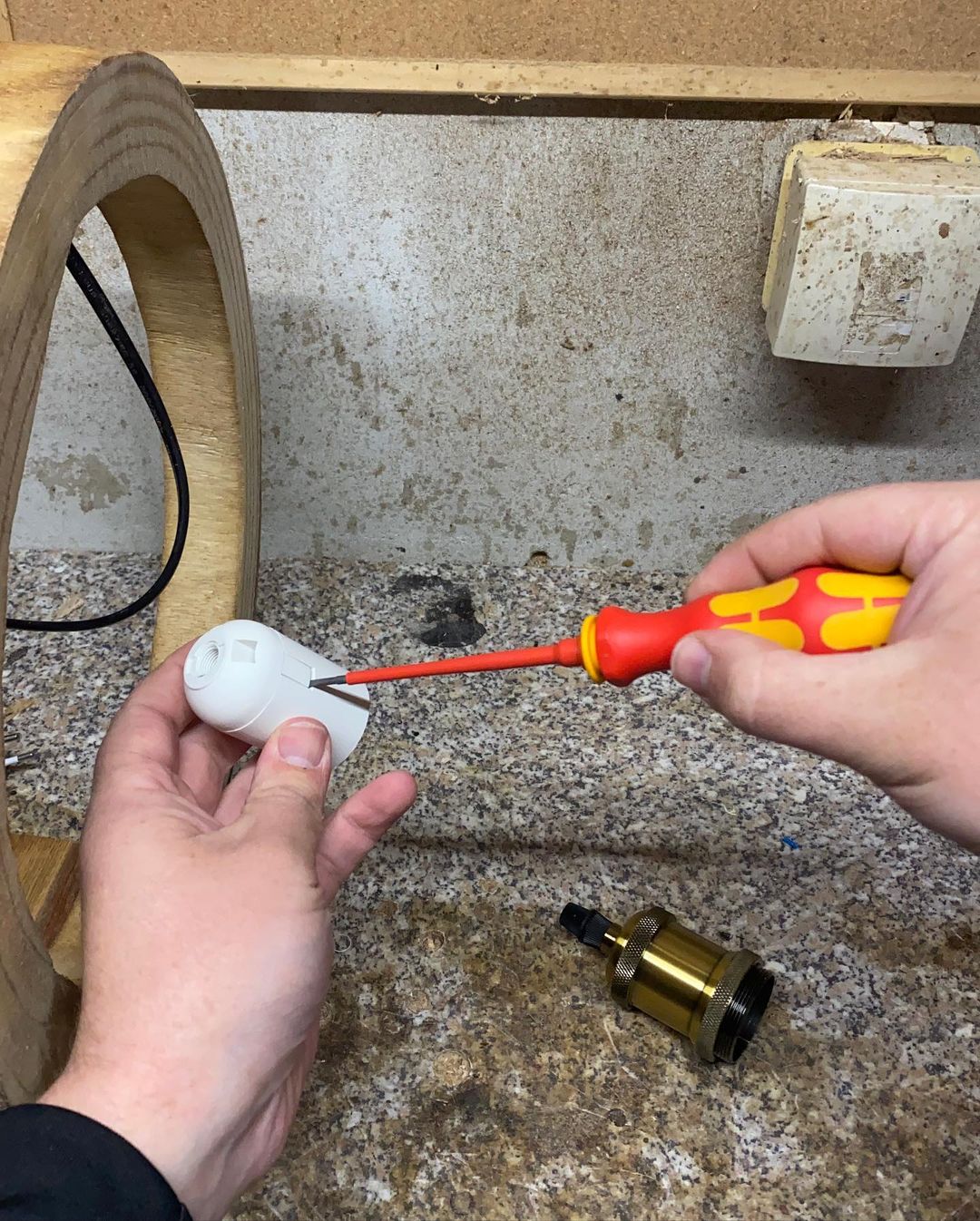 Person using a screwdriver to adjust a white electrical device