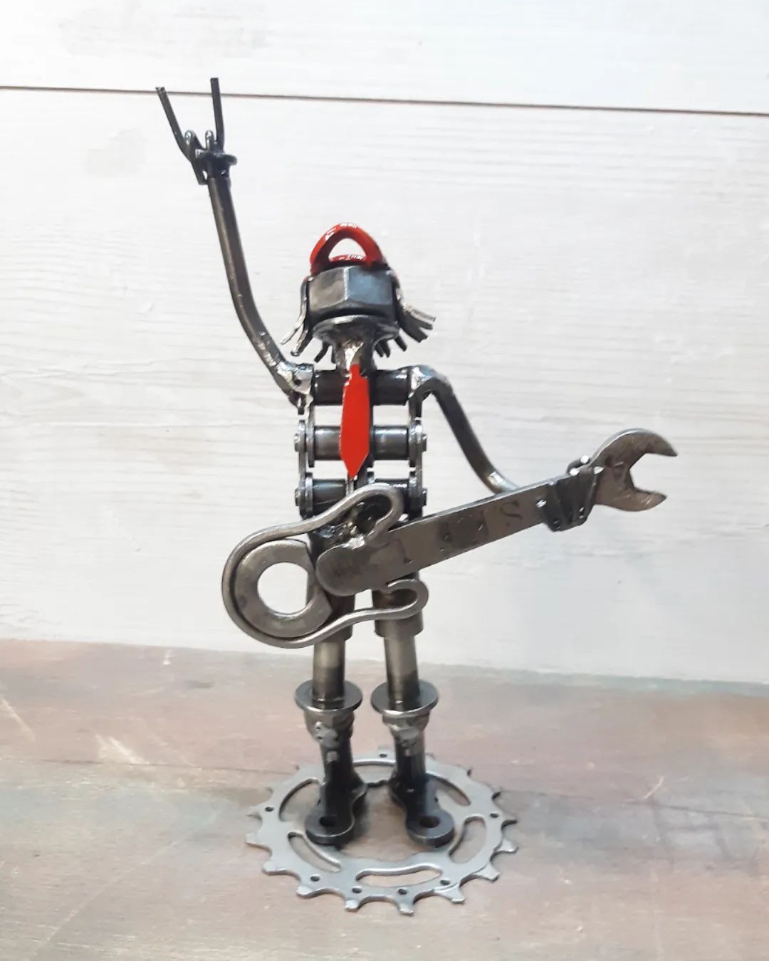 A creatively crafted metal sculpture portraying a humanoid figure playing an electric guitar.