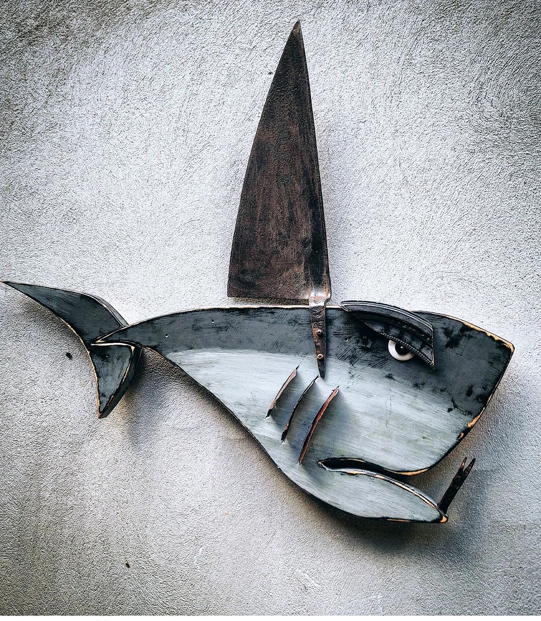 A creatively crafted metal shark sculpture mounted on a wall