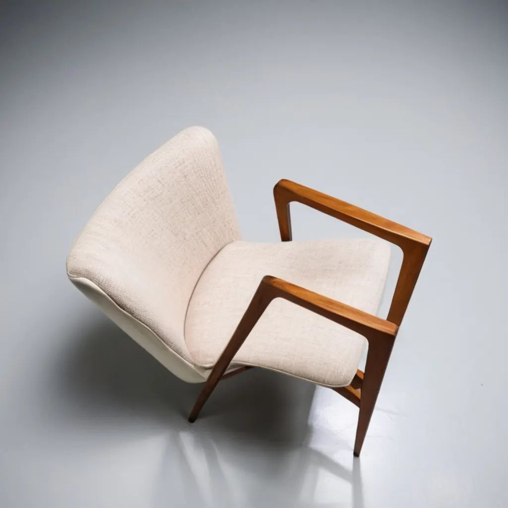 A minimalist mid-century armchair with sleek wooden armrests and cream fabric upholstery