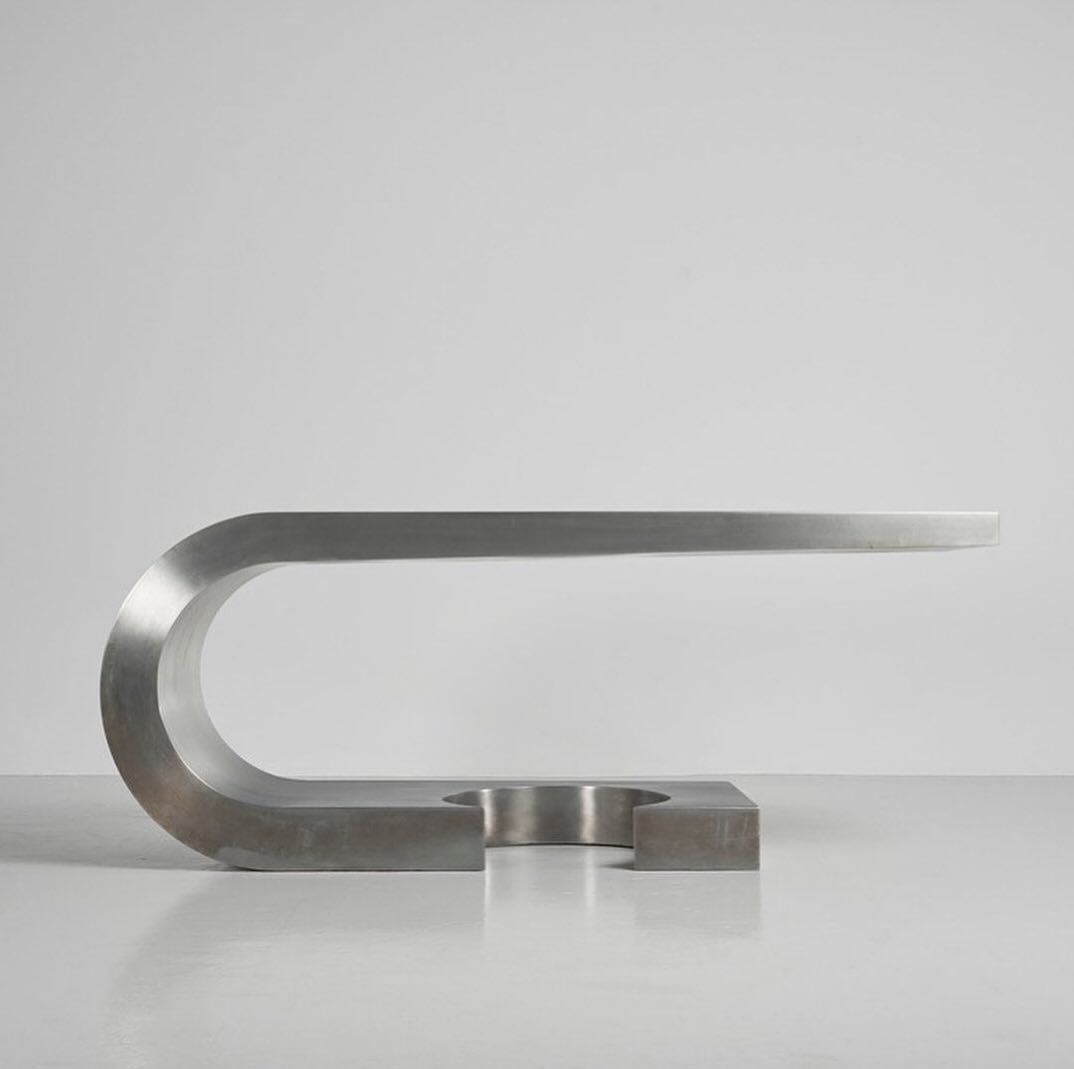 A minimalist and abstract metal bench with a smooth curve